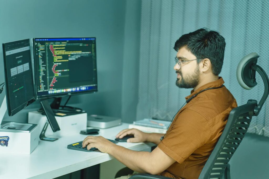 Developer working at a dual-monitor workstation in a modern office
